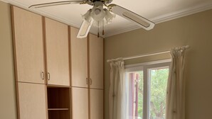Ein Schlafzimmer mit Bett, Schrank und einem Fenster mit Vorhängen.