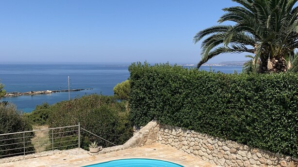 Ein Swimmingpool mit einer Steindeck und Blick aufs Meer.