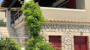 Ein zweistöckiges Haus mit einer Stein-Fassade, einer roten Tür und einem überdachten Veranda.