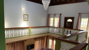 Un amplio salón con techo alto, una araña, un televisor y un sofá.