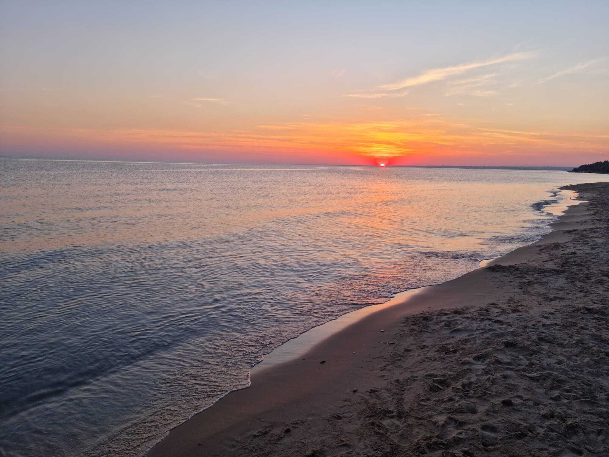 En strand med en solnedgång över vattnet.