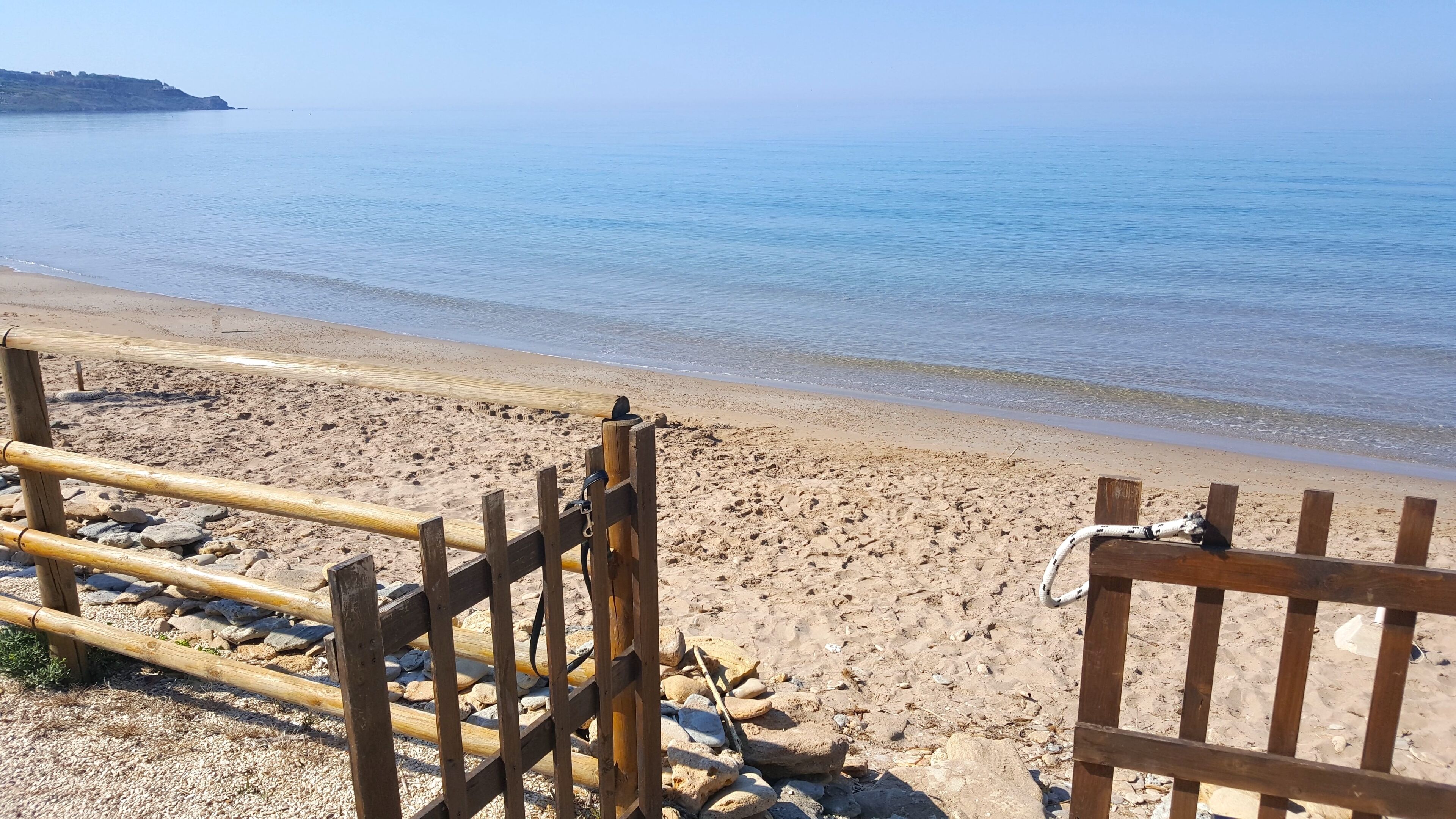 A beach with a wooden fence and rocks.