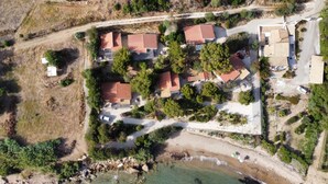 Vue aérienne d’une propriété côtière comprenant plusieurs bâtiments, une plage et une végétation luxuriante environnante.
