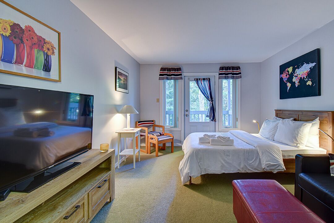 Een hotelkamer met een bed, televisie, bureau, stoel en raam met gordijnen.