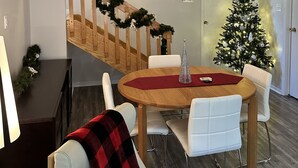 Uma sala de jantar com escada de madeira, árvore de Natal e um candelabro.