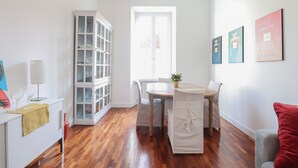 A bright room with a wooden floor, a dining table with chairs, a cabinet with glass doors, and a window. - Near Vatican Museums Rome (Roma)