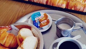 A tray with croissants, a cup of coffee, and a small bowl of butter. - HOTEL LOS ANTIGUOS (Los Antiguos)