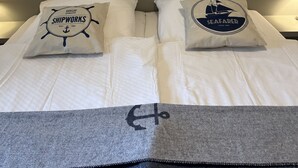 Una cama con dos almohadas, cada una con motivos náuticos.