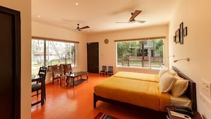 A spacious bedroom with a large bed, a ceiling fan, and a view of the outdoors through large windows. - Lhasa Ayurveda and Wellness Resort (North Paravur)