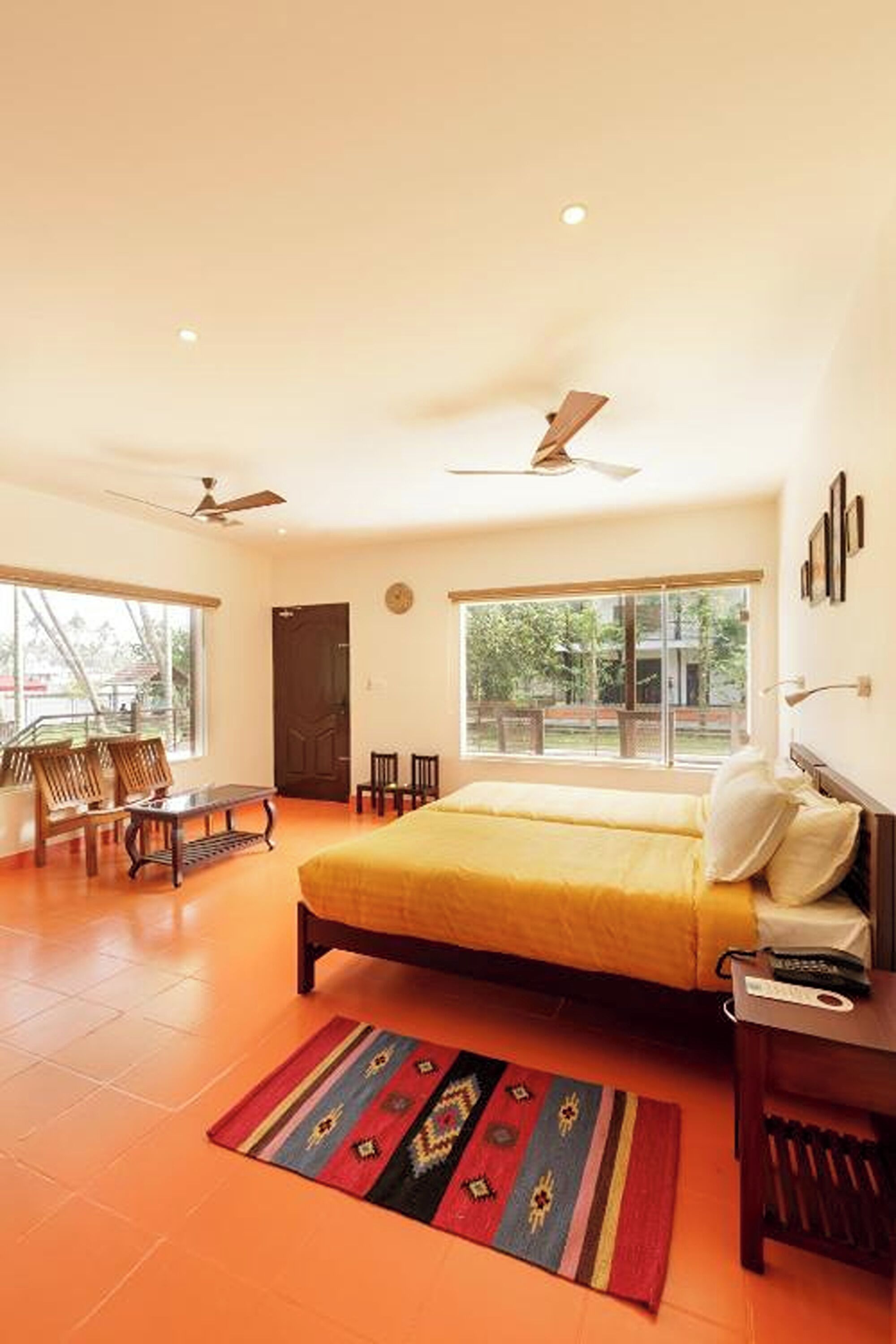 A bedroom with a bed, a desk, a chair, a window, and a ceiling fan.