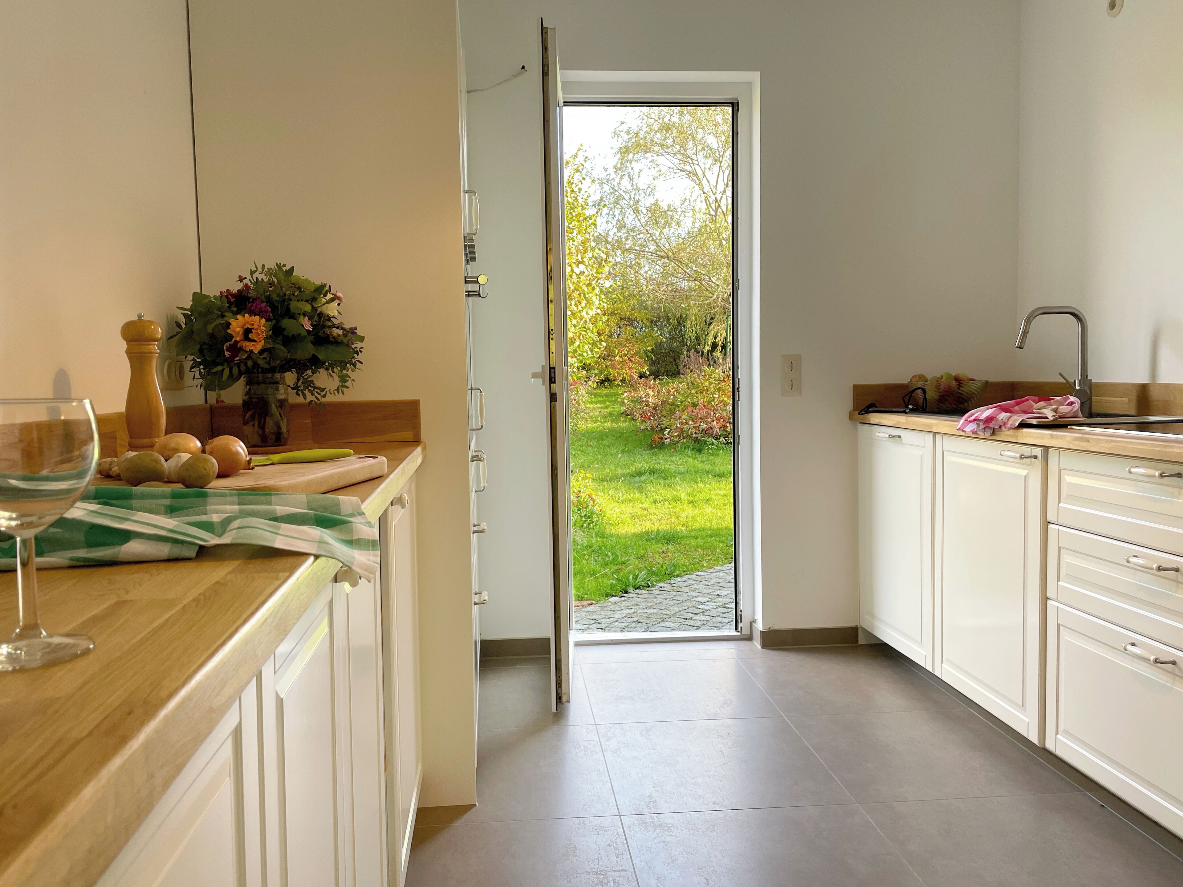 A kitchen with a view of a garden through an open door.