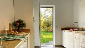 A kitchen with a view of a garden through an open door.