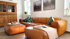 A living room with a brown leather sofa, a wooden cabinet, and two framed pictures on the wall.