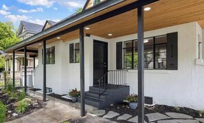 A modern house with a covered porch, a front door, and a staircase leading to the entrance. - Beautiful three bedroom home blocks from downtown (Boise)
