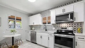 Eine moderne Küche mit weißen Schränken, einer Mikrowelle, einem Backofen und einem Geschirrspüler.