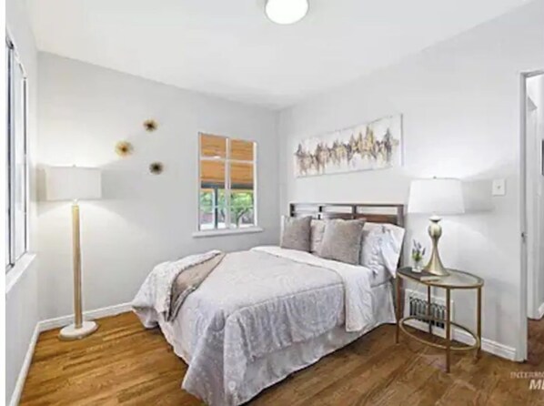 A bedroom with a bed, bedside tables, a window, and a painting on the wall. - Beautiful three bedroom home blocks from downtown (Boise)
