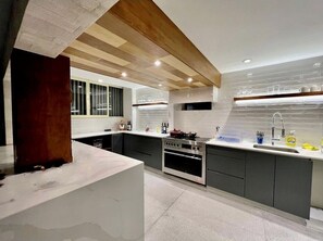 Enjoy cooking in this well-lit kitchen with an oven, stainless steel range hood, and large island with a sink.