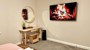 Une chambre à coucher avec un lit, un bureau, une télévision et une cheminée.