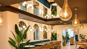 A restaurant with a high ceiling, hanging pendant lights, and a mix of wooden and upholstered furniture. - Maison Paradis Marseille (Marseille)