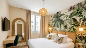 A hotel room with a bed, a desk, a chair, a television, and a large window. - Maison Paradis Marseille (Marseille)