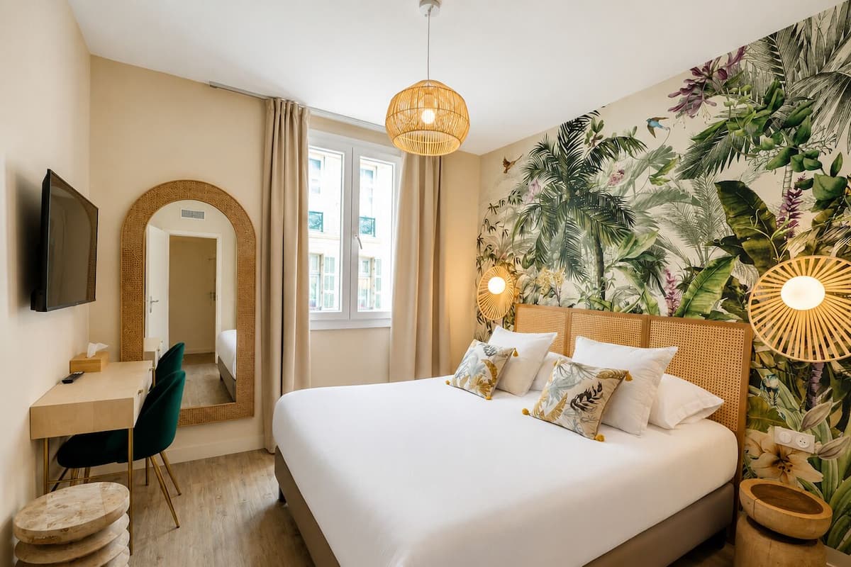 A hotel room with a bed, a desk, a chair, a television, and a large window.
