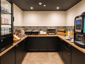 A modern kitchen with a coffee machine, breakfast items, and a fruit basket. - Maison Paradis Marseille (Marseille)