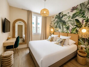 A hotel room with a bed, a desk, a chair, a television, and a large window. - Maison Paradis Marseille (Marseille)