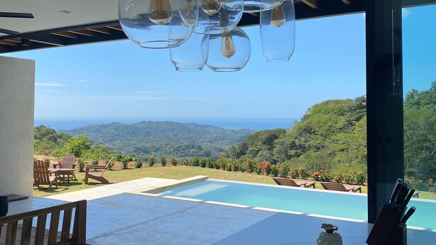 A modern interior with a pool, outdoor seating, and a view of the landscape.