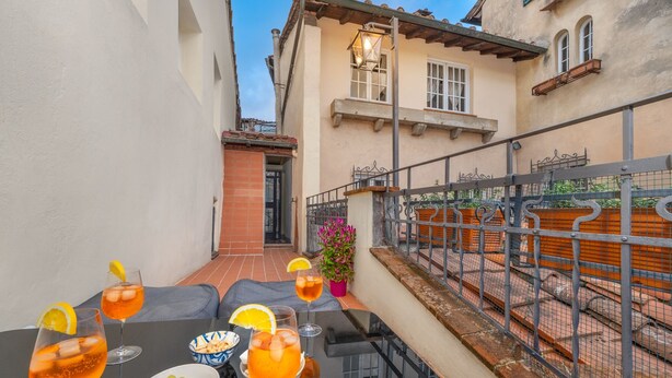 Una terraza con una mesa preparada para bebidas, un cuenco de aceitunas y una planta en maceta.