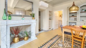 Una cocina espaciosa con chimenea de mármol blanco, un espejo grande y una mesa de comedor de madera.