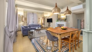 Un salón amplio con un sofá azul, una mesa de comedor de madera con sillas y una alfombra estampada.