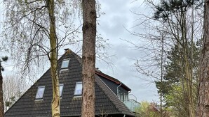 Ein Haus mit geneigtem Dach, einer Ziegelaußenwand und einem eingezäunten Garten.