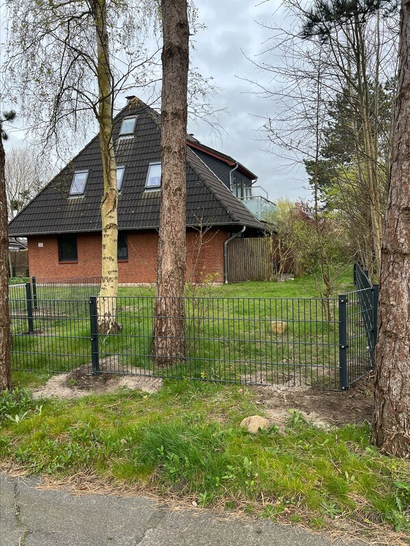 A house with a sloped roof, a brick exterior, and a fenced yard.