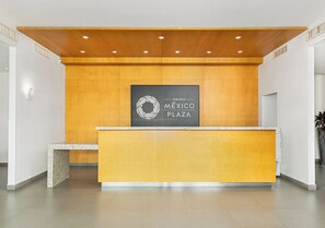 Un mostrador de recepción con un revestimiento de pared de madera y el logotipo de Grupo Mexico Plaza.