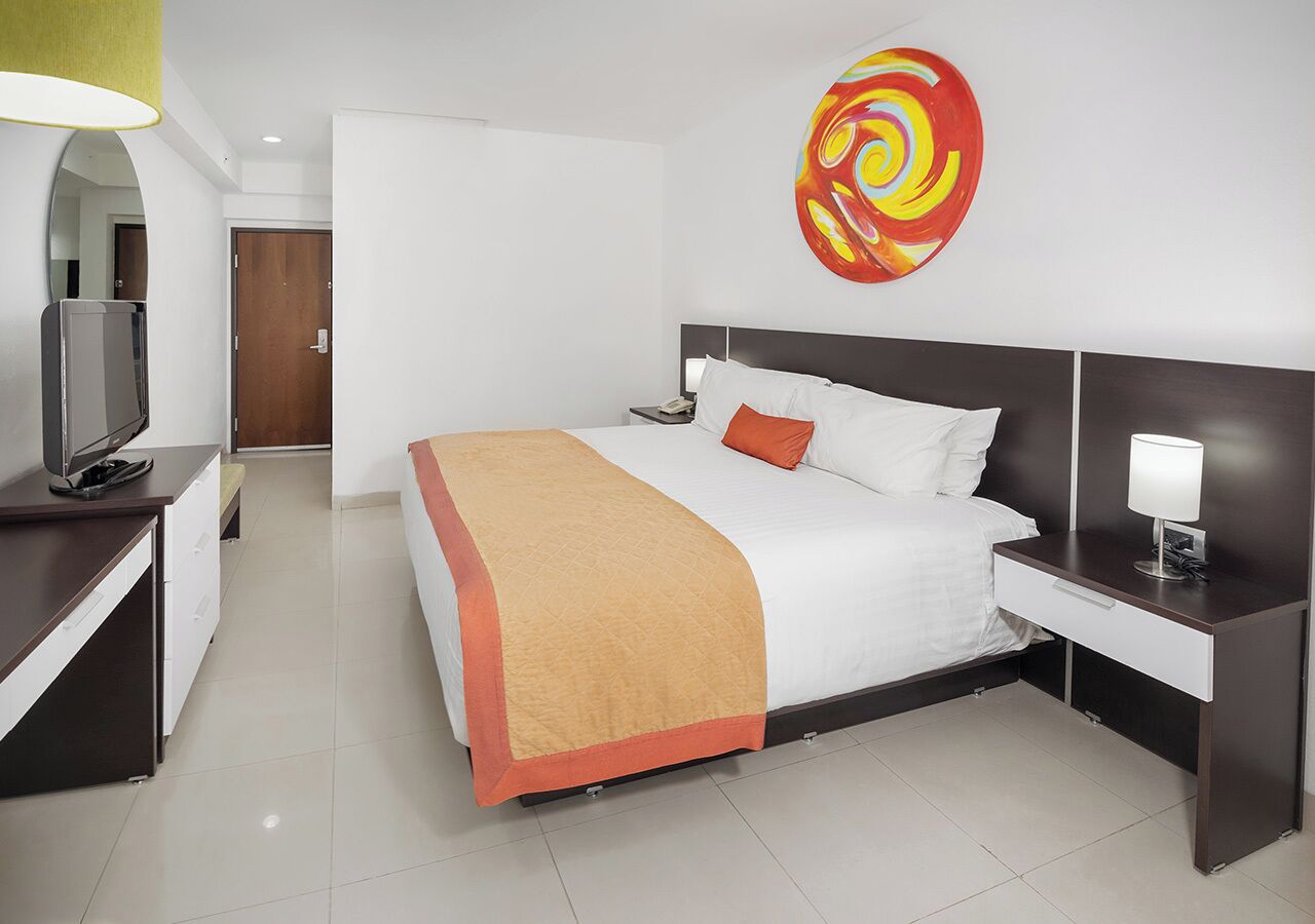 Una habitación de hotel moderna con cama, mesita de noche y televisor.