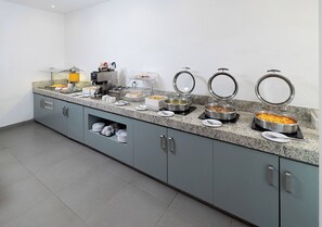 Een buffetopstelling met verschillende voedselcontainers en een koffieapparaat.