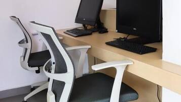 Un espace de travail comprenant deux chaises de bureau, un bureau, deux écrans et un clavier.