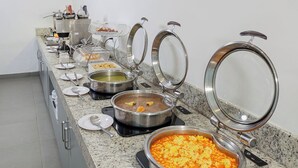 Montaje de buffet con diversos platos en ollas metálicas, cada una con su tapa.
