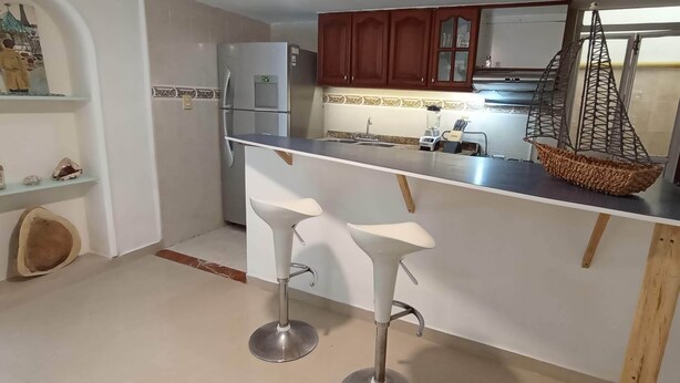 A compact kitchen with a refrigerator, a sink, and a hanging basket. - Beautiful small house close Getsemani (Cartagena de Indias)