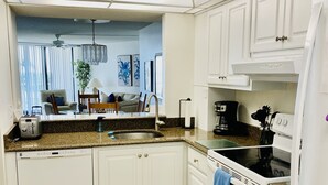 Une cuisine moderne avec des meubles blancs, un plan de travail en granit, un four encastré et un ventilateur de plafond.