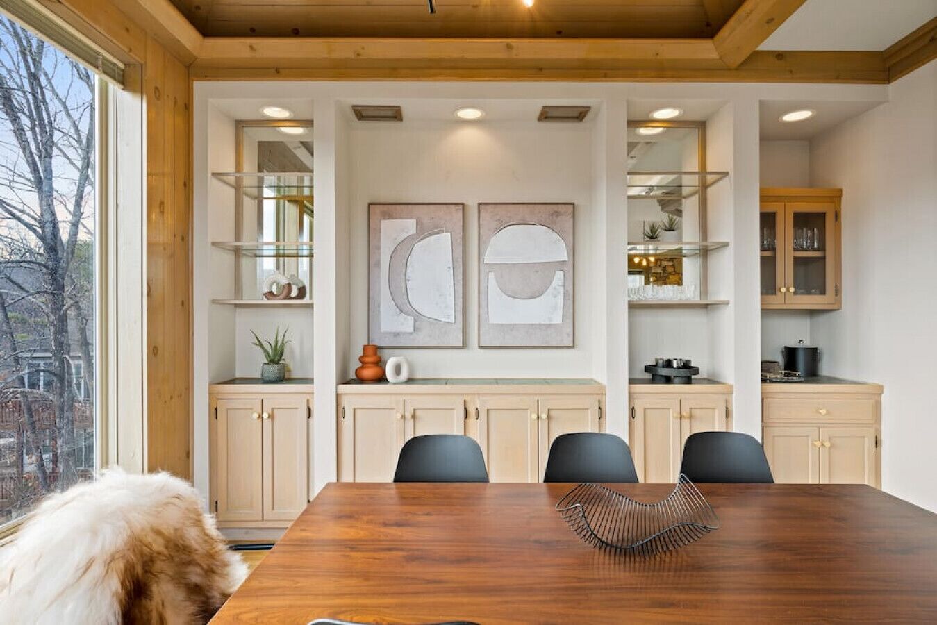 A dining area with a wooden table, chairs, and artwork on the wall.