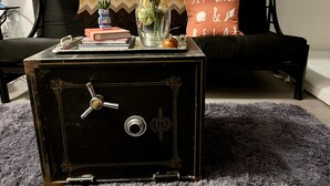 A vintage safe with a lock, a vase with yellow flowers, a book, and a decorative item on a table.