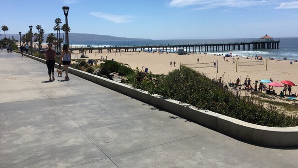 A beach with a pier extending into the ocean, a walking path, and beachgoers. - Charming Studio w/ Fireplace & Kitchen — Steps to Sand (Manhattan Beach)