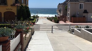 A coastal street with a sidewalk leading to the beach, houses on either side, and a clear view of the ocean. - Charming Studio w/ Fireplace & Kitchen — Steps to Sand (Manhattan Beach)