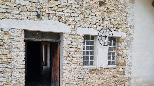 Un edifici de pedra amb una porta de fusta i una petita finestra amb un rellotge.