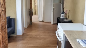 Una cuina moderna amb sòl de fusta, fogó blanc i taulell de fusta.