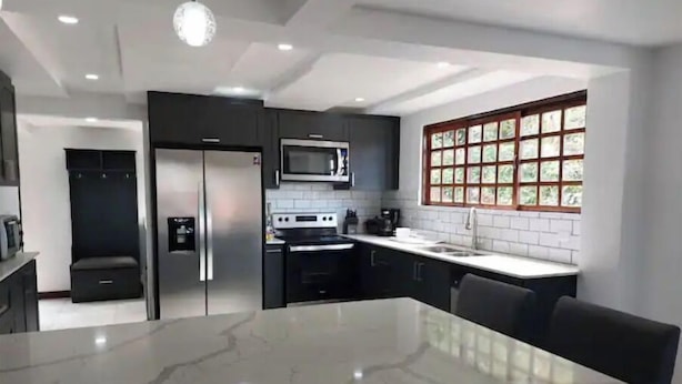 Una cocina moderna con encimera de mármol, electrodomésticos de acero inoxidable y un amplio ventanal con diseño de cuadrícula.