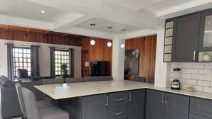 Una cocina moderna con una isla grande, muebles oscuros y un comedor con sofá y sillas.