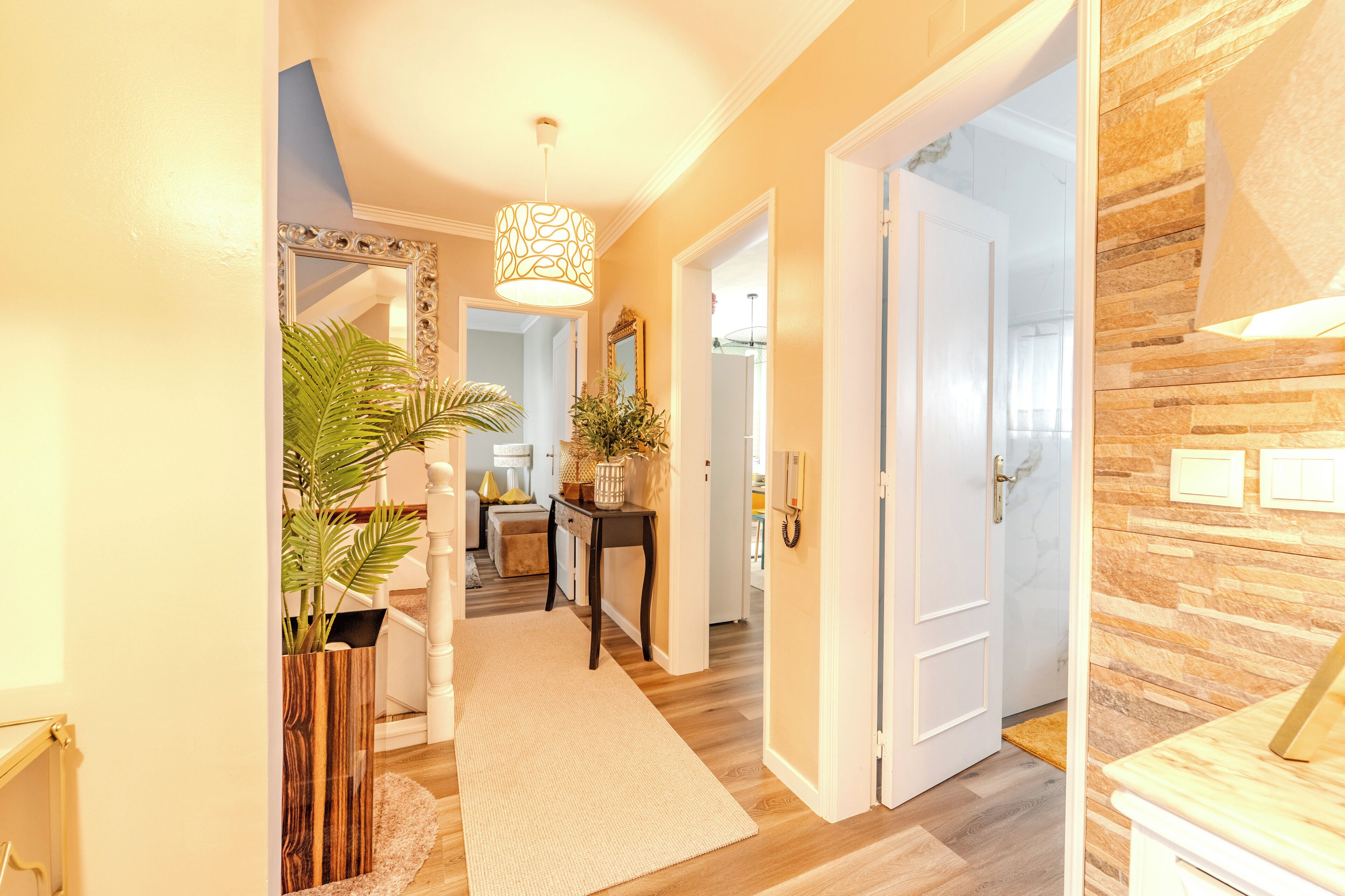A hallway with a wooden floor, a white door, and a mirror on the left.