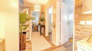A hallway with a wooden floor, a white door, and a mirror on the left.